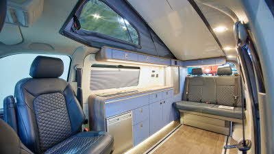 Campervan interior, blue kitchen, rising roof, grey fridge, leather driver's seat