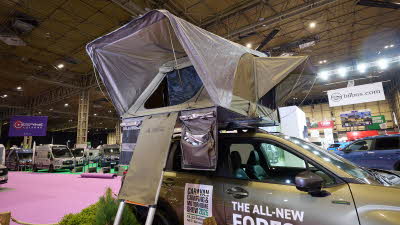 The ARB 4x4 Accessories Esperence is displayed on a green Subaru Forester.  It has khaki and cream canvas.  The window and door are open and there is hanging pocket for outdoor shoes.