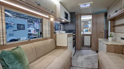 Swift Challenger SE 480's interior has pale wooden furniture with beige upholstery.  The washroom is at the rear and its door is open.