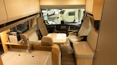 The MORELO HOME 78L has cream leather upholstery, the front seats are facing the lounge area and there is a white table at the centre.  The kitchen area is in the bottom left.