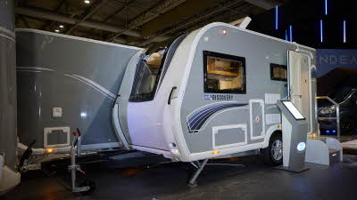 Bailey Discovery D4-2 exterior which is pale grey.  The door is open and there are steps to gain easy access to the interior.  The skylight is open and there is an interactive pedestal next to the steps