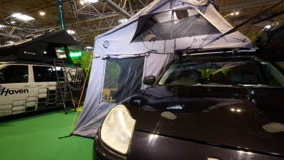 The Latitude Tents Pioneer XL is displayed on a black Porsche. It has grey canvas walls and a pale grey roof. It also has an awning.