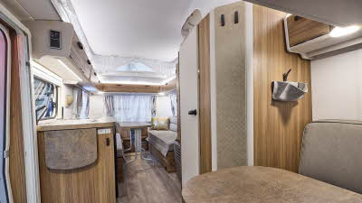 Interior of the Eriba Touring 540 Legend with grey sofas, beige accents and a wooden floor.  To the rear there are two sofas and a free standing table.