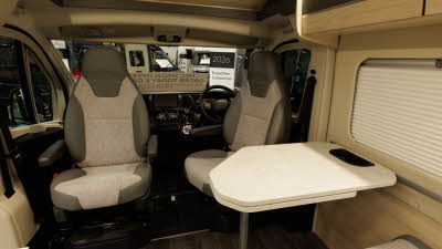 The Auto-Trail Expedition 68 XL Flex has brown and cream upholstery.  Both the driver and front passenger seats are swivelled to face the centre of the van, there is a marble effect extending table.