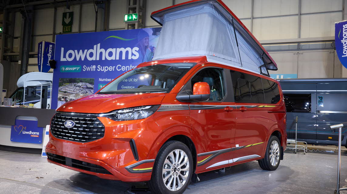 The Swift Monza is orange, its pop top roof is open and the canvas is pale blue.
