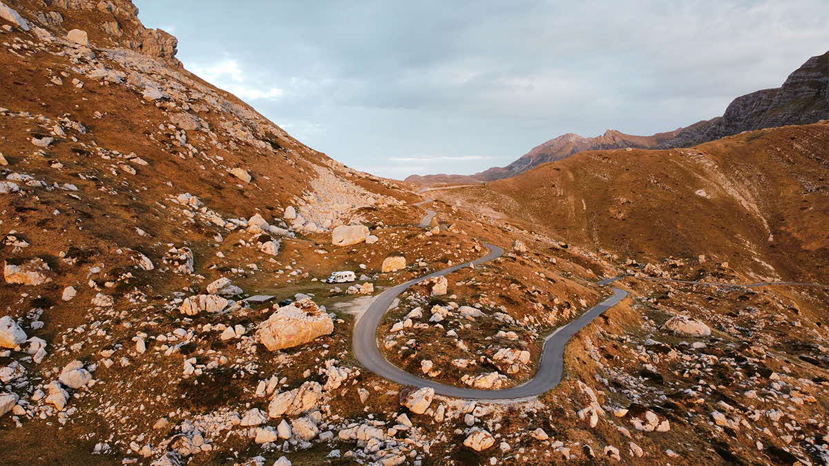 An aerial view of the Big European Odyssey motorhome on a winding road going through the mountains of Montenegro