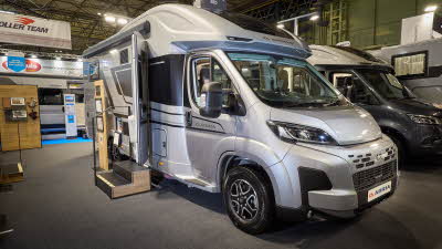 The Adria Matrix Supreme has a silver exterior. The habitation door is open and there are two steps to gain easy access. There is an information board to the left of the steps.