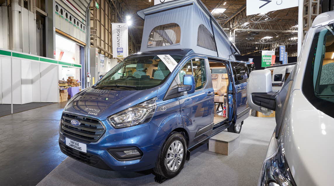 Vantage LUNA has a blue exterior.  The sliding door is open showing the interior, there is a strip light inset on one of the steps.  The rising roof is fully risen and the built in awning is extended.