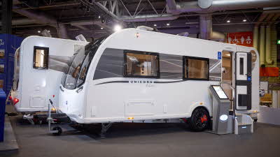 Bailey Unicorn Deluxe Madrid’s exterior is white with a grey and yellow patterned decal from the front to the rear.  The entrance door is open and there are two metal steps to gain easy access.  There is an interactive display board to the left