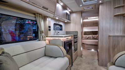 Elddis Crusader Aurora's interior has pale wood furniture and its upholstery is gold and cream with black piping.  The bedroom is to the rear and it has a large skylight.