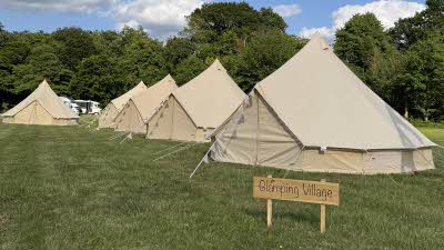 neat little bell tents lined up in the glamping village with bunting outside each