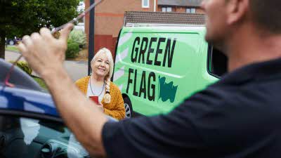 Woman smiling whilst a greenflag repair man fixes her vehicle