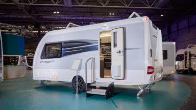 Swift Challenger Exclusive 480’s exterior is white with grey sides, it has a black and blue decal.  Its entrance door is open with a step to gain easy access.  There is an information board to the left of the door.  