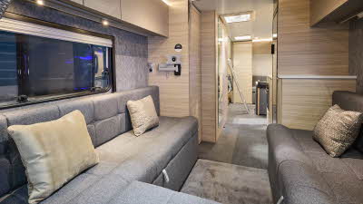 The Adria Altea 622 DK Avon has a front u shaped grey sofa with beige cushions.  The furniture is pale wood.  Towards the rear there is a ladder to gain easy access to the rear fixed bunks.