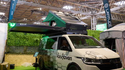 The Latitude Tents Explorer is displayed on a cream Volkswagen campervan.  It has green canvas and a hard top roof.  It has an extended platform.