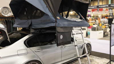 The Latitude Tents Scout has blue and black canvas, it has a silver ladder to gain easy access.  It is shown on a silver car.