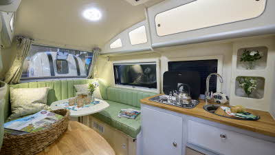 Barefoot Caravan Country Living x Barefoot’s interior is cream with pale green upholstery.  There are wooden work surfaces.