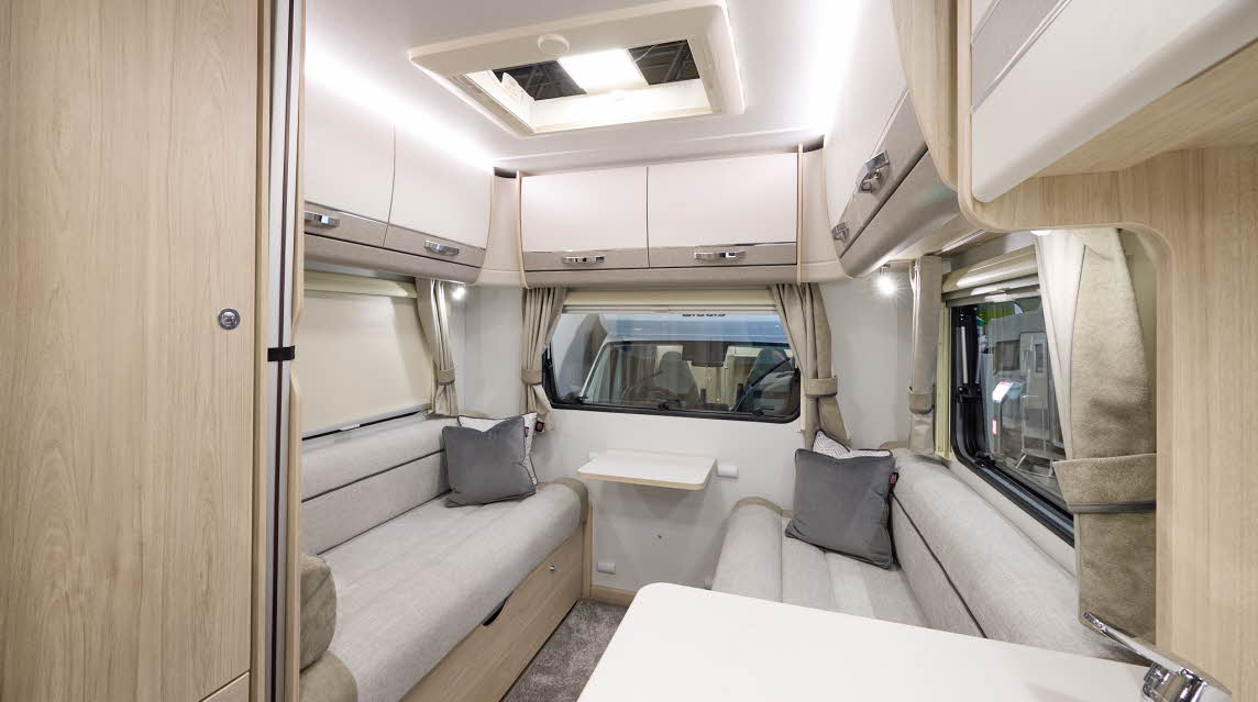 The Elddis Autoquest 196 has beige carpet with cream and pale brown cabinets.  The upholstery is cream and pale brown with dark brown piping.  The sink is in the front.  There is a rear lounge with two sofas.