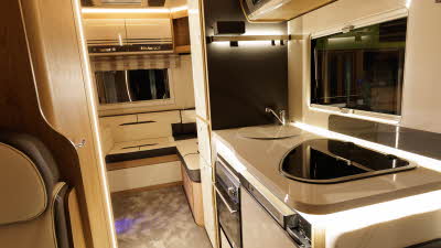 The Roller Team Auto-Roller 746 has cream and brown upholstery and has a rear lounge.  The kitchen is to the right and there is a skylight above the lounge.