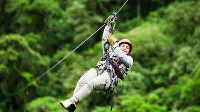 Lady zipwiring at height with a lush green background