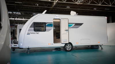Swift Sprite Grande Quattro FB has a white exterior with grey and turquoise graphics.  It's door and skylight are open.  It has a single axle.