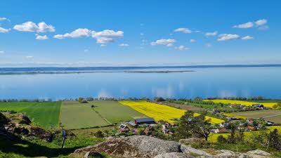 View of Lake Vättern in Sweden in summer with sky reflected in the calm water next to green fields