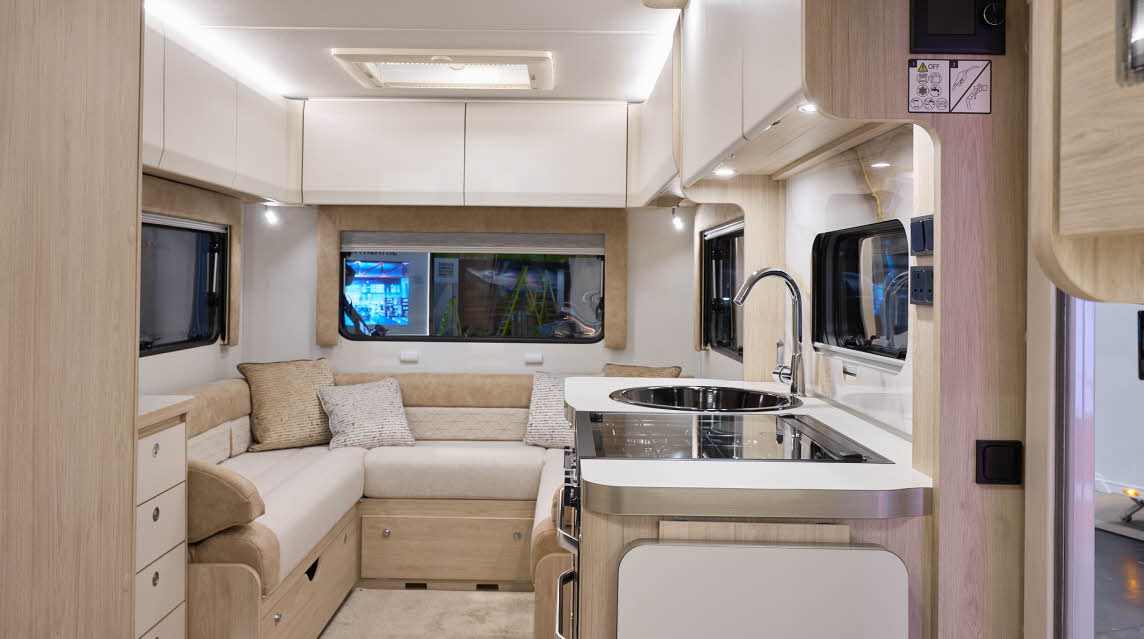 The Elddis Avalon 295 has beige carpets and cream cabinets.  The upholstery is cream and pale brown.  The kitchen is placed in the middle and just behind there is a u shaped lounge.  There is a skylight above the lounge.