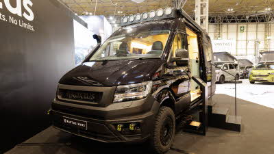 The Kaktus Adventure Vans Dune is black, its sliding door is open and there are three steps to gain easy access.  On the cab roof there are seven spotlights.