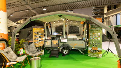 The OPUS Voyager is pale green and has brown canvas.  There are two chairs outside the unit.