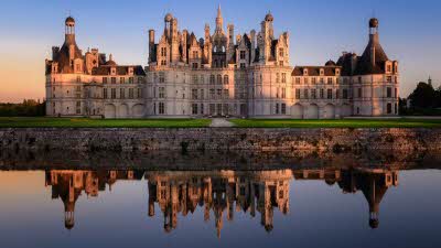 Château de Chambord reflecting in the water, during a sunset sky