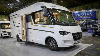 Eura Mobil Integra Line IL’s exterior has white body and has grey and gold decals.  The habitation door is open and there is a step to gain easy access. 