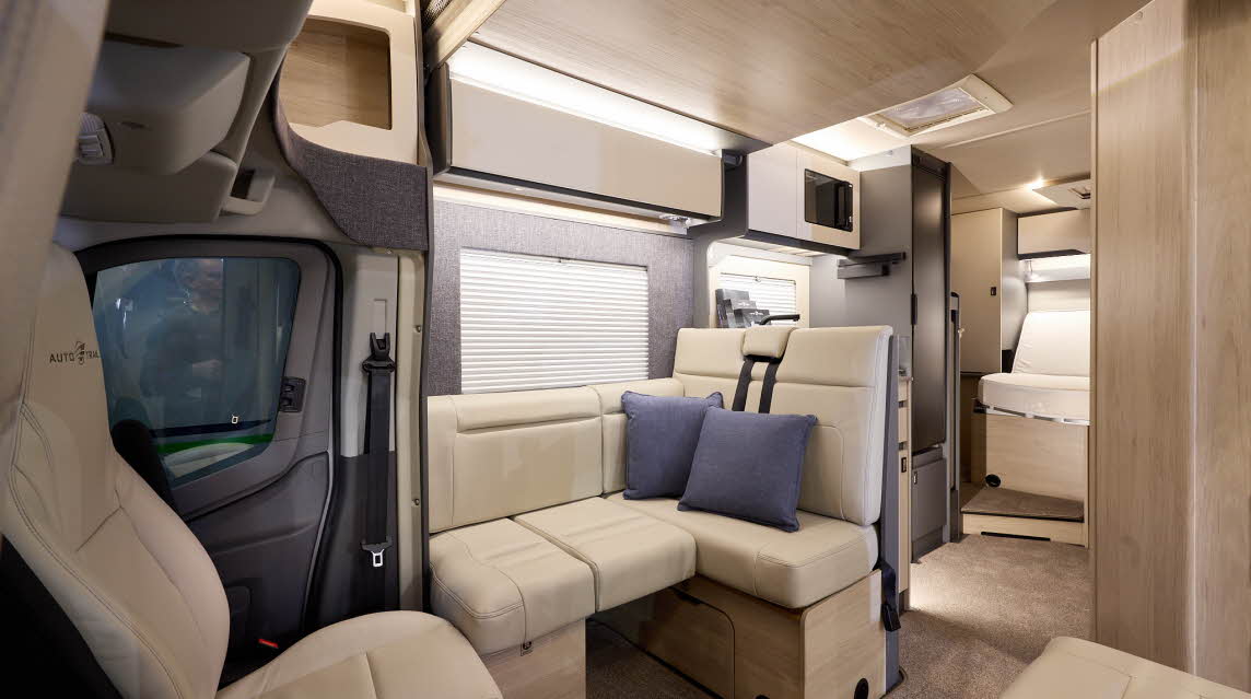 The Auto-Trail F-Line F74 has beige carpets, with pale wood cabinets with cream overhead lockers.  The upholstery is cream leather.  There is a step leading to the rear fixed bed.