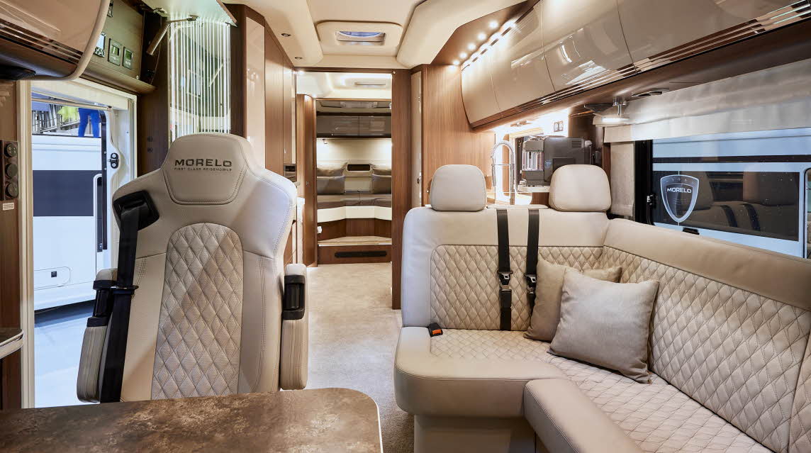 MORELO EMPIRE LINER 93LB has pale embossed upholstery showing three rear travel seats.  The floor has a cream carpet.  Towards the rear of the vehicle there is a large fixed bed.  