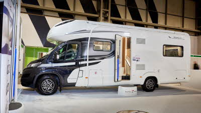 Auto-Trail Frontier Scout exterior, the motorhome has a grey cab with a white body, the habitation door is open showing into the interior, with a step to gain easy access.  There is a blue Auto-Trail umbrella in the door.
