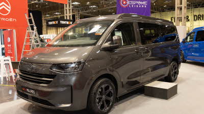 The Hillside Leisure Cromford is dark grey, its rising roof and sliding door are closed.  There is a step in front of the sliding door.