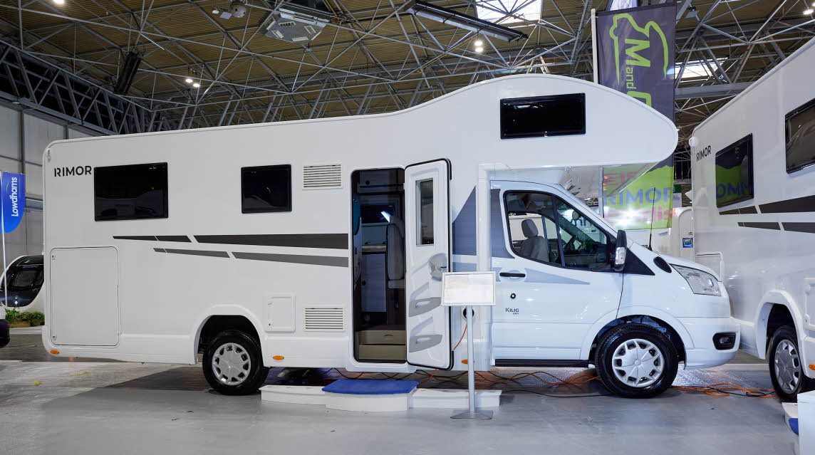 Rimor Kilig 695 has a predominately white exterior with grey graphics. The habitation door is open with a step to gain easy access. 