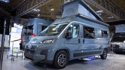 The Swift Carrera 244 is grey with black trim, it's habitation step is extended. The rising roof is fully extended.
