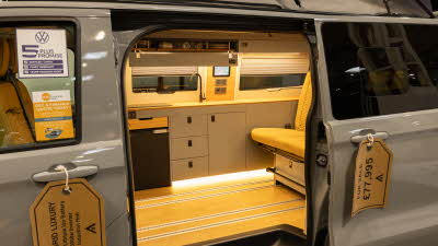 The Wildtracks Campervans Panoramic has tan leather upholstery and has grey cabinets.