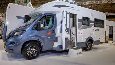 Roller Team T-Line 700 has a grey cab with a white exterior and grey/red decals. The habitation door is open showing the interior with a step to gain easy access. The wheels are black alloys.  