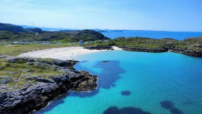 View from above looking out over the beautiful clear turquoise waters with a sandy beach and rocky shorlines