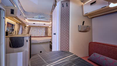 Eriba Touring 530 Urban Tango Red interior, it is white and cream with red upholstery.  There is a dinette at the front.  The fixed bed is beyond the kitchen.  