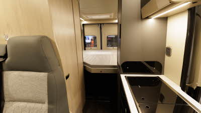 The Auto-Trail Expedition 68 XL Flex has brown and cream upholstery.  There is a fixed rear bed.  The cabinets are pale wooden.  The kitchen unit is in the right bottom corner.