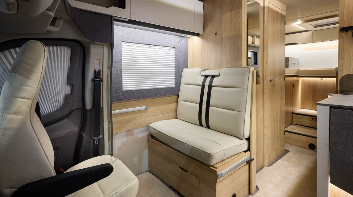 The Auto-Trail Excel 690T has beige carpet, with pale wood cabinets with white overhead lockers.  The upholstery is cream leather.  There are two steps to the rear fixed bed.