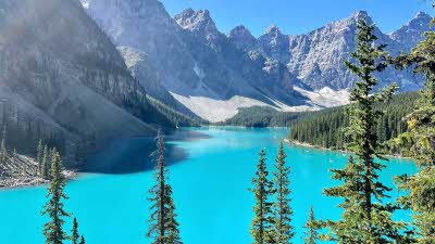 View of Lake Moraine behind the tree lined mountain side on a clear sunny day