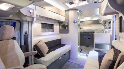 Bailey Alora 69-4S’ interior has cream and dark brown upholstery with beige/dark brown cushions.  The furniture is white.  There are two sky lights in the fixed roof.  The wall of the washroom is curved and there is a fixed bed to the rear.  