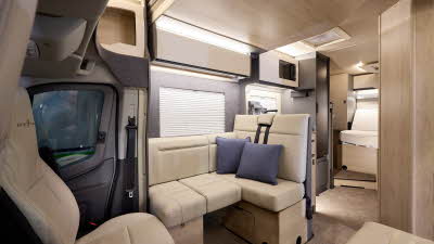 The Auto-Trail F-Line F74 has beige carpets, with pale wood cabinets with cream overhead lockers.  The upholstery is cream leather.  There is a step leading to the rear fixed bed.