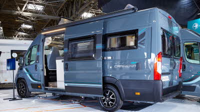 Swift Carrera 184 has a blue exterior.  The sliding door is open showing the interior.  The alloy wheels are black and silver.