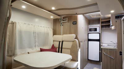 Benimar Tessoro 481 has pale upholstery.  It has grey carpets and has a rear kitchen where there is a large fridge freezer with a microwave above it.