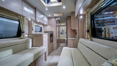 Xplore 585's interior has wooden furniture and has cream sofas with black piping.  There is a central kitchen.  There is a second lounge to the rear.