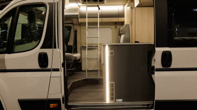 The Auto-Trail Expedition 68 has brown and beige upholstery, there is a silver ladder which leads to the rising roof's bed.